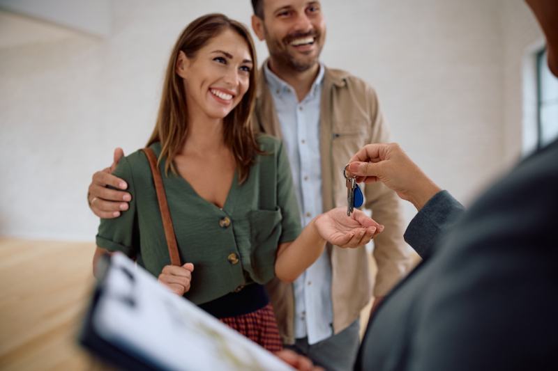 Happy woman and her husband getting keys from real estate agent while buying a new apartment