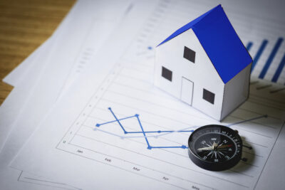 House model and compass on plan background, Real estate concept.